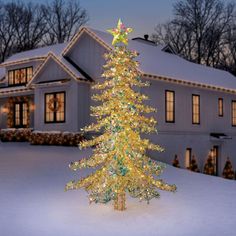 a lighted christmas tree in front of a house