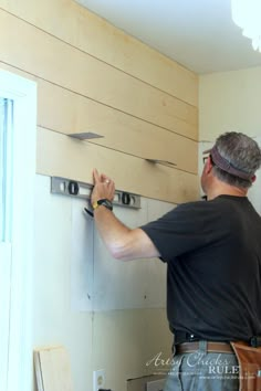 a man is working on the wall in his kitchen with wood planks and metal brackets