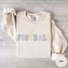 a white sweatshirt with the word football on it, sitting on top of a wooden floor