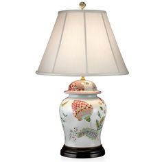 a lamp with a white shade on it and a flowered vase in the center