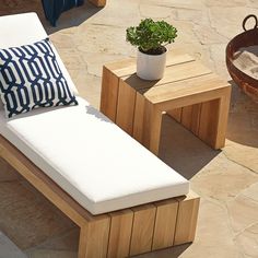 a wooden bench sitting next to a potted plant on top of a stone floor