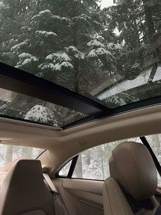 the interior of a car with snow covered trees in the background