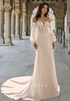 a woman in a white wedding dress standing on a stone floor with columns and arches behind her