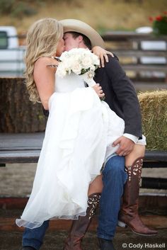 a bride and groom kissing on a bench