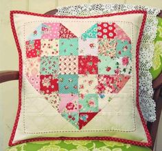 a heart shaped pillow sitting on top of a green chair next to a lace doily