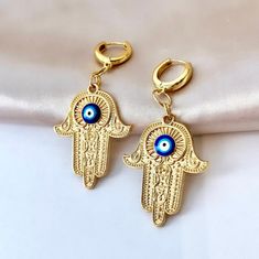 Are you looking for the perfect Hand of Fatima earrings for someone special this summer? Or a unique pair of evil eye dangle earrings to spoil yourself? Made with tarnish-free stainless steel, plated with 18K gold and featuring a delicate evil eye cabochon, my gold Hamsa earrings are the perfect compliment to any outfit idea! My evil eye hoop earrings are a great gift idea for any special occasion to all the women in your life. You can't go wrong when gifting my evil eye Hamsa earrings to your b Arabic Earrings, Evil Eye Hamsa, Hamsa Earrings, Dangle Earrings Gold, Gold Hamsa, Earrings Summer, Evil Eye Earrings, Ringe Gold, Gold Signet Ring