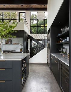 an open kitchen with black cabinets and white counter tops is seen in this modern home