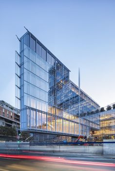 a large glass building with lots of windows on it's side and cars passing by