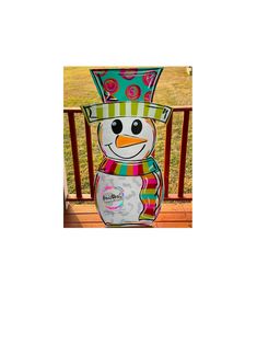 a snowman sitting on top of a wooden deck