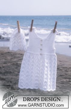 a white dress hanging on a clothes line next to the beach with waves in the background