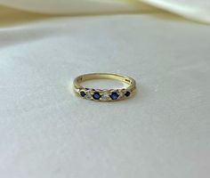 a yellow gold ring with three blue sapphire stones on it, sitting on a white cloth