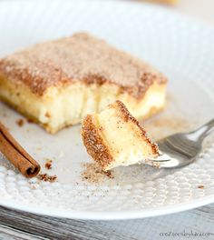 a piece of cake on a plate with cinnamon sticks