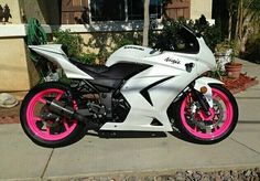 a white and pink motorcycle parked in front of a house