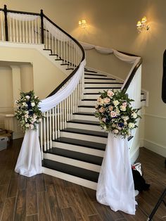 two bouquets of flowers sit on the steps of a wedding ceremony venue, decorated with white and black ribbon