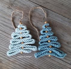 two crocheted christmas trees hanging from strings on a wooden floor, one is blue and the other is white