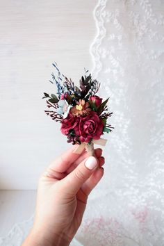 a person holding a small bouquet of flowers in their hand on a lace tablecloth