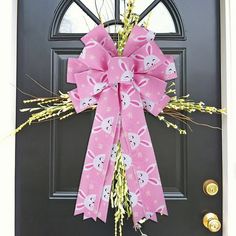 a pink bow on the front door of a house that is decorated with easter bunnies