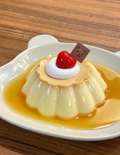 a small dessert is sitting on a white plate with sauce and a cherry in the middle