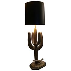 a table lamp with a black shade on it and a cactus shaped object in the middle