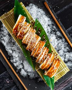 an overhead view of some food on a plate with chopsticks and ice cubes