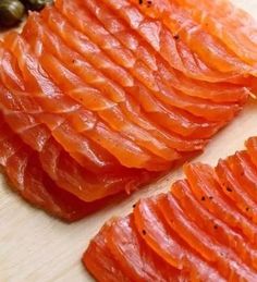 sliced up salmon on a cutting board with olives