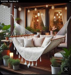 a white hammock sitting on top of a wooden floor next to potted plants