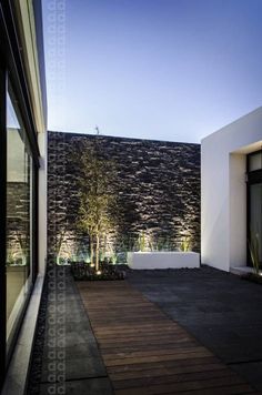 an outdoor area with a wooden walkway and stone wall in the background at night time