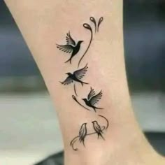 a small tattoo on the ankle with two birds flying around it and vines growing out of them