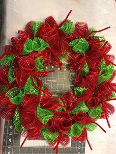 a red and green christmas wreath sitting on top of a piece of paper next to scissors