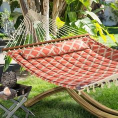 an orange and white hammock sitting on top of a grass covered field next to a potted plant