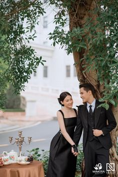 a man and woman standing next to each other under a tree