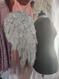 mannequins and dresses on display in front of a white backdrop with feathers