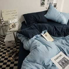 an unmade bed with blue sheets, pillows and pictures on the wall above it