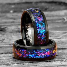 two wedding bands with blue, pink and purple glitters are on top of each other