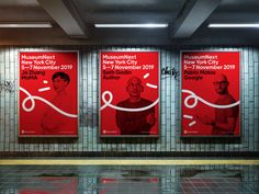 three red posters on the wall in a subway station