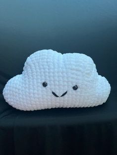 a white cloud pillow sitting on top of a black couch