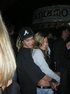 two young women hugging each other at a club or bar with people in the background