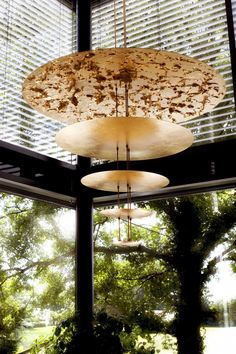 three circular lights hanging from the ceiling in a room with large windows and trees outside