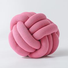 a pink ball that has been made out of yarn and is sitting on a white surface