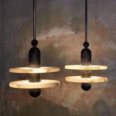 three lights hanging from the ceiling in a room with concrete walls and flooring behind them