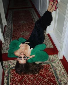 a woman is laying on the floor with her feet up and wearing green fur coat