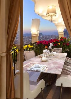 an outdoor dining area overlooking the city and flowers in bloom, with chandeliers hanging from the ceiling