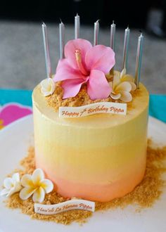 a birthday cake with candles and flowers on it's top is sitting on a plate