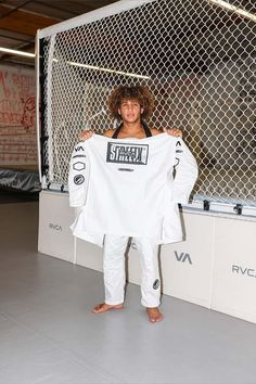 a man holding up a white shirt in front of a fence