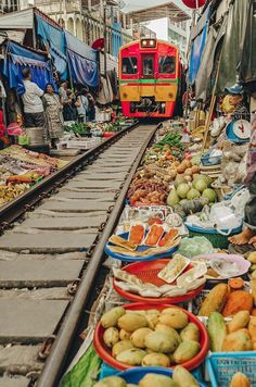 an outdoor market with fruits and vegetables on the tracks