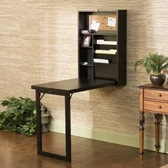 a desk with a book shelf above it and a potted plant next to it