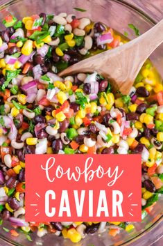 a bowl filled with black beans, corn and cilantro next to a wooden spoon