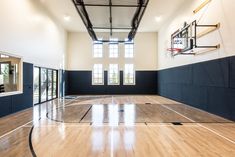 an indoor basketball court with hard wood flooring and glass doors leading to the outside