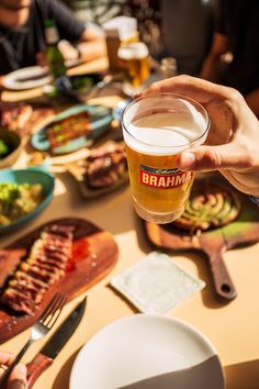 a person holding a beer over a table full of food