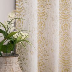 a potted plant sitting next to a window with yellow and white curtains behind it